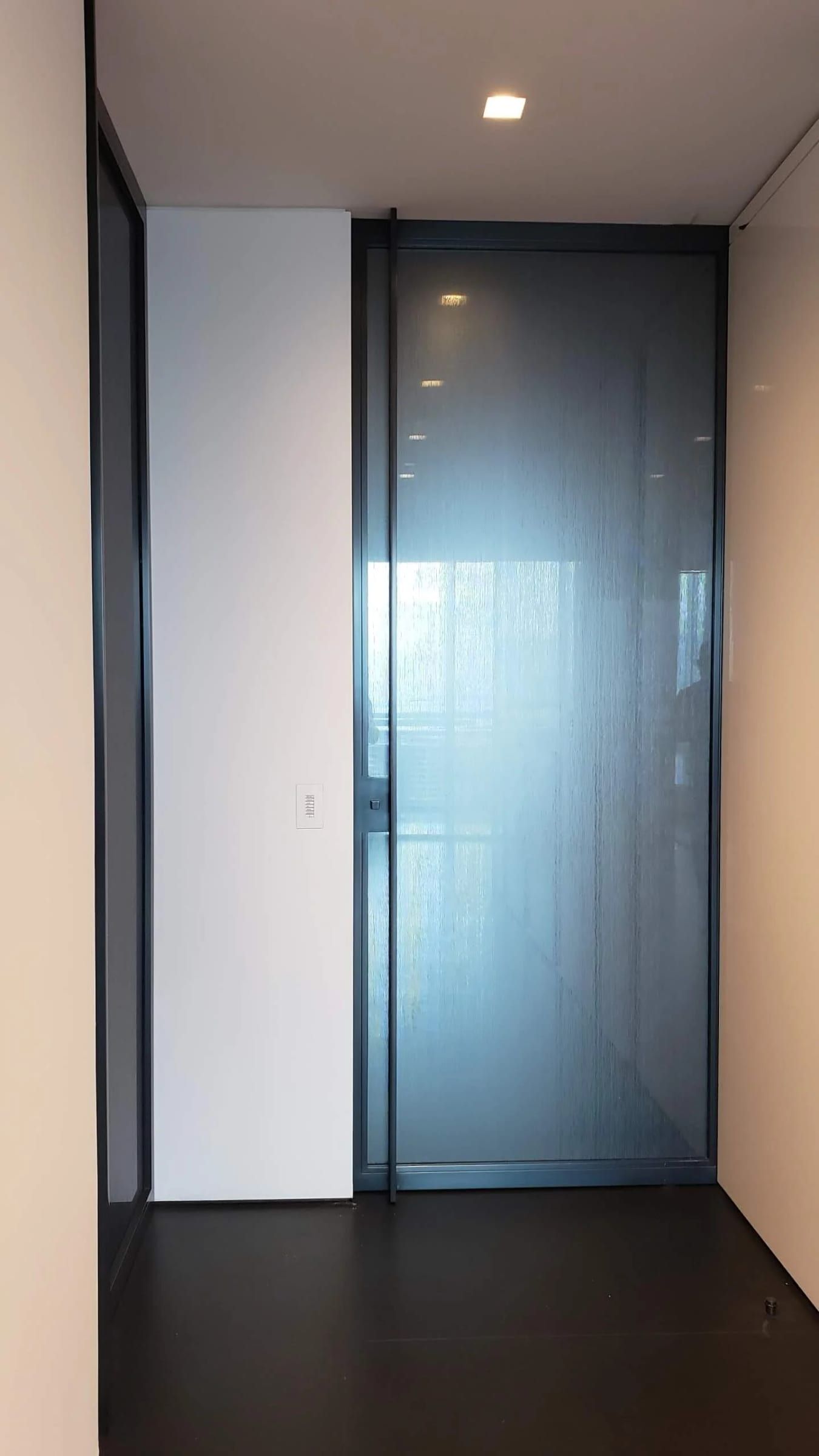 Narrow blackened stainless and glass door in a hallway