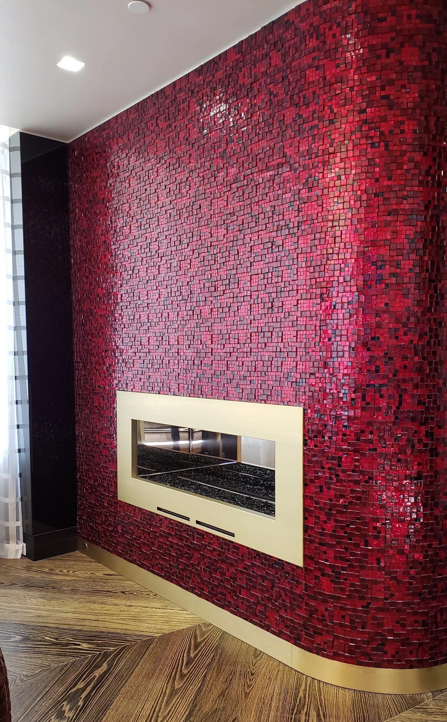 Fireplace in a brass surround set into a red glass mosaic wall