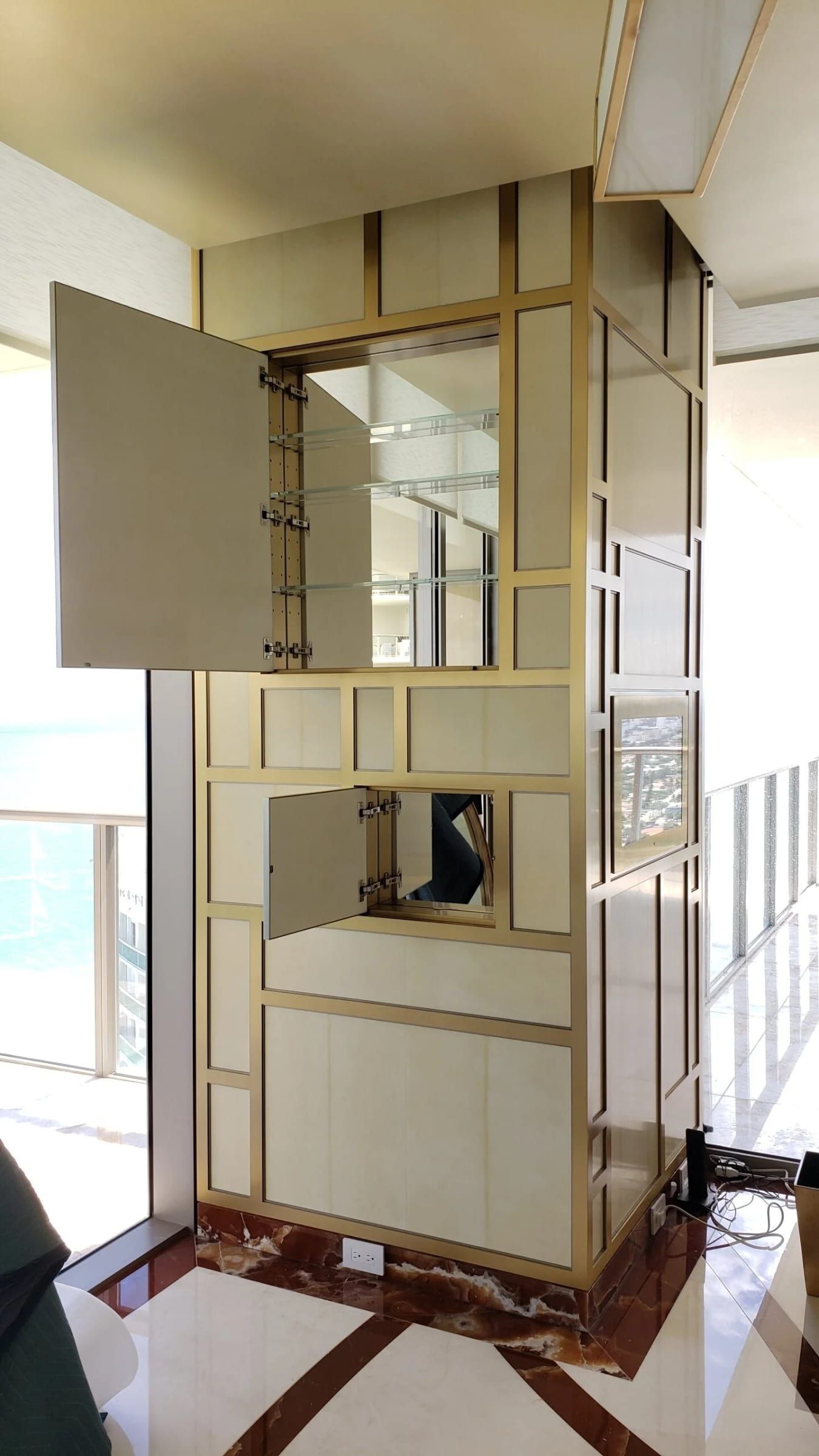 Column clad in brass-framed panels, its concealed door open