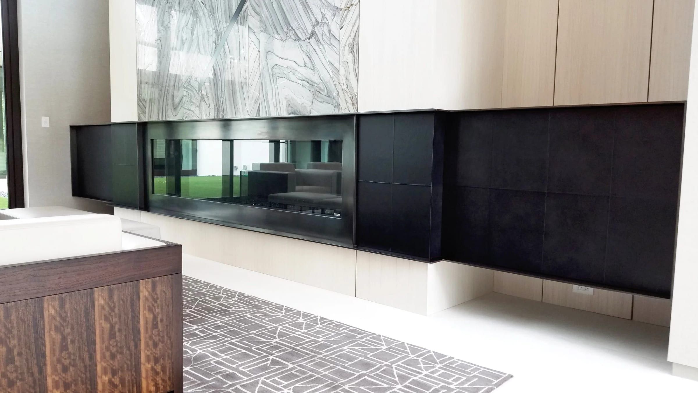 Media wall with blackened steel cabinetry under a stone feature panel