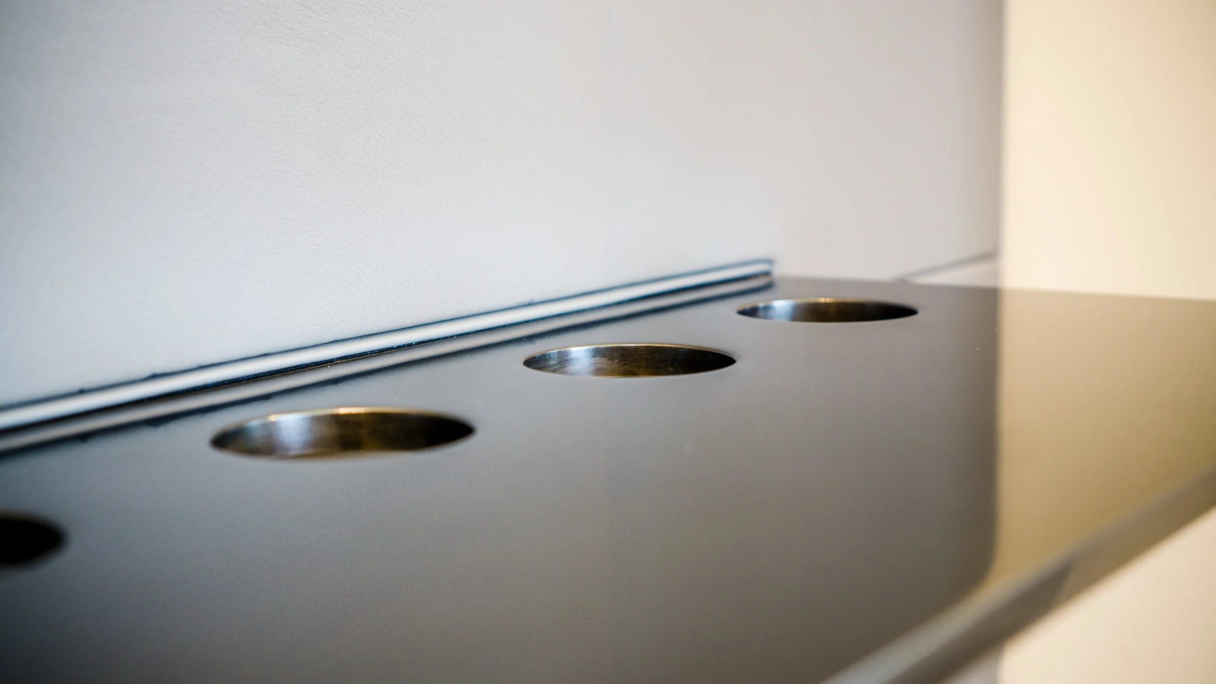 Blackened steel panel with brass-lined circular openings, close detail